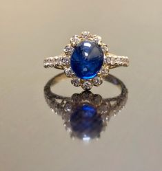 "DeKara Designs Collection Art Deco Inspired Extremely Elegant Halo Opal Diamond Engagement Ring. Metal- 90% Platinum, 10% Iridium. Stones- 1 Natural Oval Cabochon Ceylon Blue Sapphire 2.85 Carats, 26 Round Diamonds F-G Color VS1 Clarity 0.65 Carats. Size- 4-12 An Amazing Art Deco Inspired Ceylon Blue Sapphire Halo Diamond Engagement Ring Made in 18K Yellow Gold. The ring features a beautiful a beautiful Ceylon Blue Sapphire that is Oval in shape and cabochon cut. The sapphire is gracefully set Classic Sapphire Cabochon Rings, Elegant Sapphire Cabochon Rings, Luxury Cabochon Sapphire Ring For Wedding, Elegant Cabochon Sapphire Ring, Luxury 14k Gold Sapphire Wedding Ring, Elegant Sapphire Cabochon Jewelry, Luxury Hallmarked Oval Cabochon Sapphire Ring, Elegant Cabochon Sapphire Jewelry, Blue Cabochon Sapphire Ring In 14k Gold