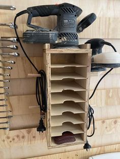 a cordless sanding machine sitting on top of a wooden shelf filled with lots of tools