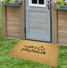 a door mat with the words play house on it in front of a wooden shed