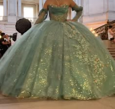 a woman in a green ball gown with gold sequins