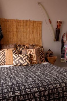 a bed with black and white pillows on top of it next to a bamboo headboard