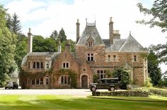 an old car is parked in front of a large house