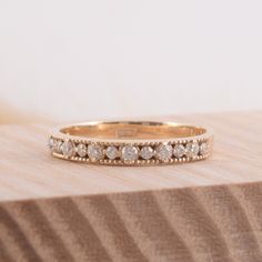 a gold wedding band with five diamonds on it sitting on top of a wooden surface