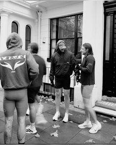 several people standing on the sidewalk in front of a building