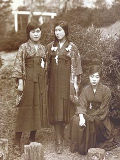 an old photo of three women standing next to each other in front of shrubbery