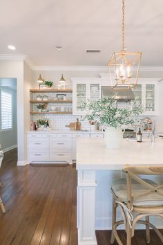 a large kitchen with white cabinets and wooden flooring, along with a center island