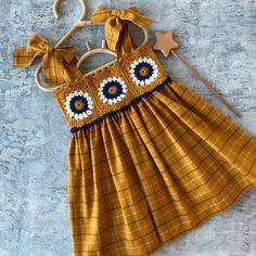 a yellow dress with blue and white flowers on the front is attached to a hook