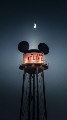 a water tower with a sign that says walt's studio on it at night