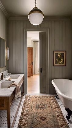 a bathroom with two sinks, a bathtub and a rug on the floor in front of it