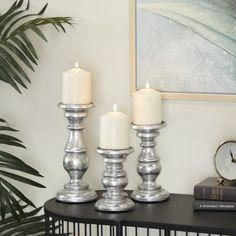 three silver candles are sitting on a table