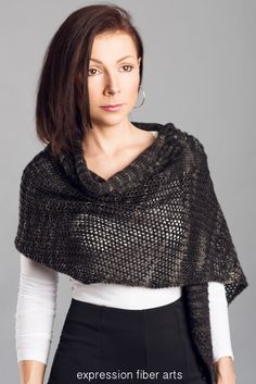 a woman wearing a knitted shawl with the words expression fiber arts on it