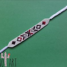 a white string bracelet with red and black hearts on it, sitting on top of a green surface