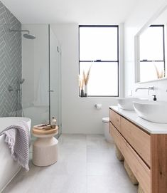 a bathroom with two sinks and a bathtub in the middle, along with large windows