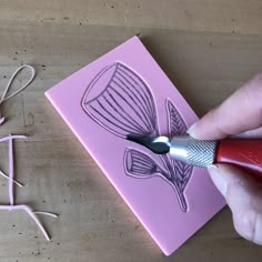 a person is using scissors to cut out the word love on a piece of pink paper