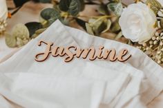 the name jasmine is placed on top of a napkin next to some flowers