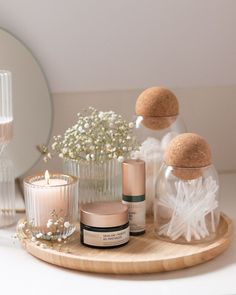 a wooden tray topped with bottles and candles next to a mirror on top of a table