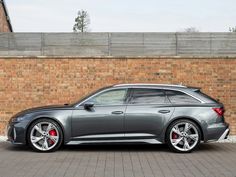 a grey car parked in front of a brick wall