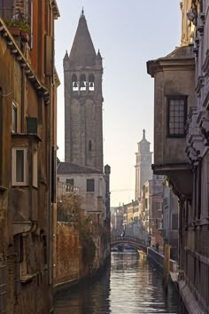 a river running through a city with tall buildings on both sides and a clock tower in the background