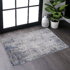 a large area rug in front of a window with potted plants on the floor