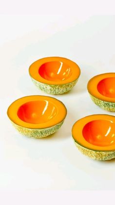 four orange and green bowls sitting on top of each other in front of a white background