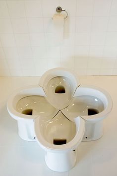 three white flower shaped toilets in a bathroom