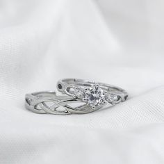 two white gold wedding rings on top of each other, with one diamond in the middle