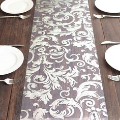 the table runner is decorated with silver and white damasks on wood flooring