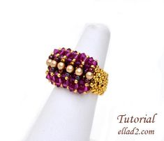 a gold and pink beaded ring sitting on top of a finger