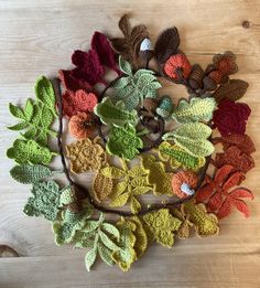 crocheted leaves arranged in a circle on a wooden surface