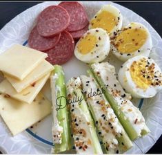 a white plate topped with eggs, cheese and asparagus next to crackers