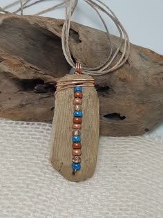 a piece of wood with beads hanging from it's end on a rope necklace