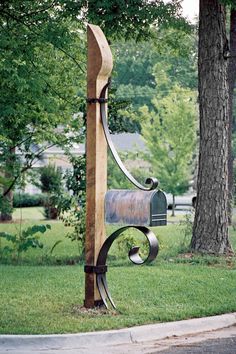 a mailbox attached to a wooden post in the grass next to a large tree