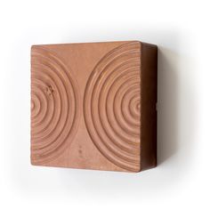 a wooden block with two circles on the front and one circle on the back, mounted to a wall