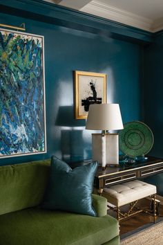 a living room with blue walls, green couches and a painting on the wall