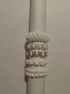 a stack of bracelets sitting on top of a white pole next to a wall