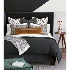 a bed with black headboard and pillows on it