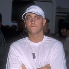 a man with his arms crossed wearing a white hat