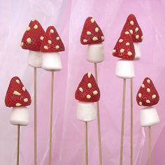 red and white mushrooms sitting on top of marshmallows in front of a pink background