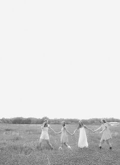 four girls are holding hands in a field