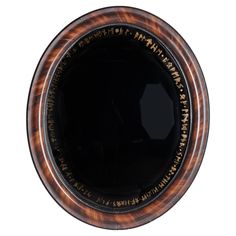 a black and brown plate with writing on the inside is shown in an oval frame