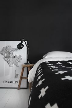 a black and white bedroom with a large painting on the wall next to a bed