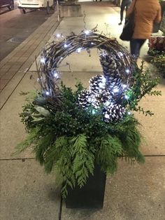 a planter filled with pine cones and greenery sitting on the side of a street