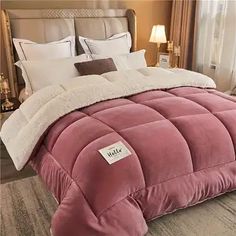 a bed with a pink comforter and pillows