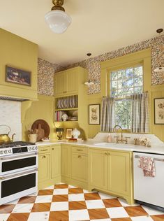 a yellow kitchen with checkered flooring and white stove top oven in the center