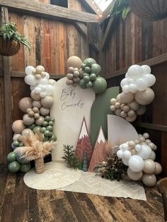 an outdoor display with balloons and greenery on the ground in front of a wooden fence