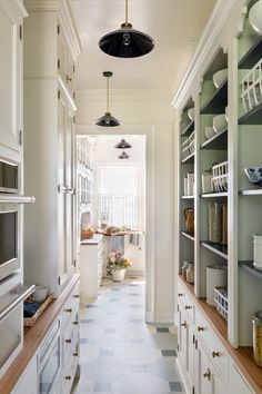 a long narrow kitchen with white cabinets and drawers