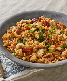 a bowl filled with rice and meat on top of a table next to a fork