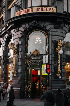 people are walking in front of a building with ornate decorations on the door and windows