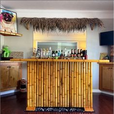 a bamboo bar with lots of bottles on the top and above it, in front of a mirror