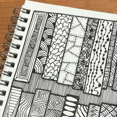 a notebook with some doodles on it sitting on top of a wooden table next to a pen